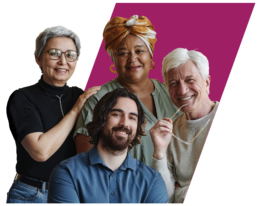 Four individuals of different ages, genders, and ethnicities embracing one another while smiling at the camera